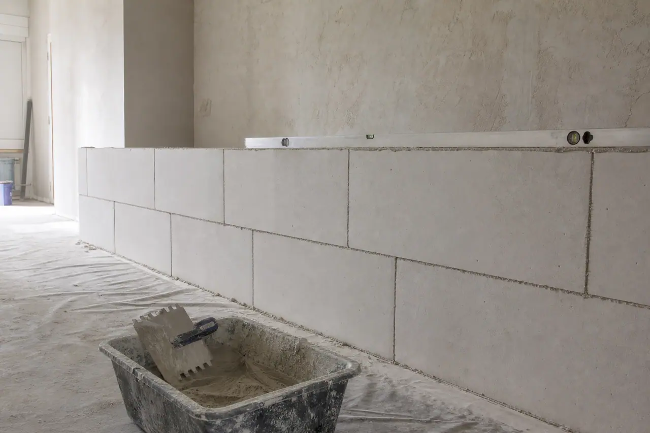 Cloison en carreaux de plâtre montée à mi-hauteur, joints décalés, niveau posé dessus