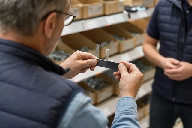 Client comparant une vis et une cheville avec une règle en magasin.
