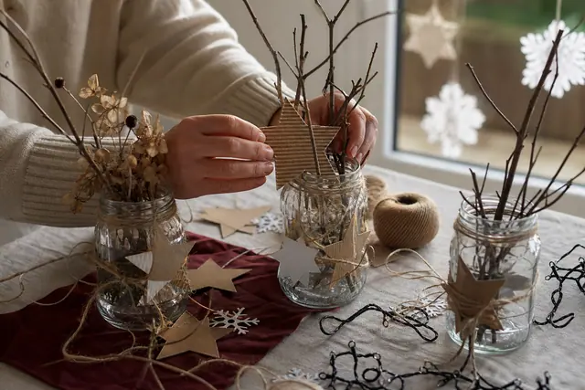 Décorations de Noël en carton, bocaux et papier récupérés sur une table.