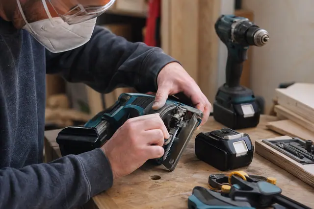 Perceuse, scie sauteuse et accessoires 18 V préparés sur un établi.
