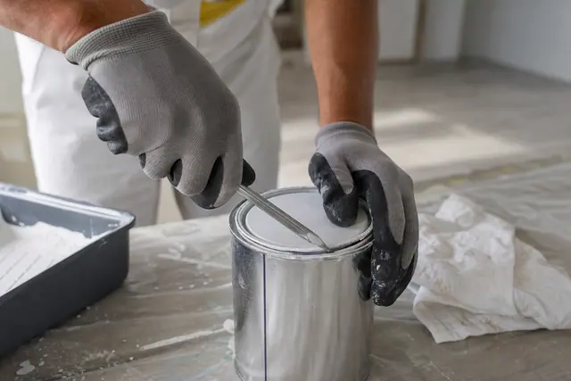 Ouverture progressive d’un pot métallique de peinture avec un ouvre-pot propre.