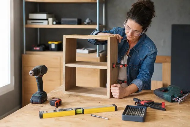 Établi domestique avec perceuse sans fil, niveau, mètre et outils de coupe.