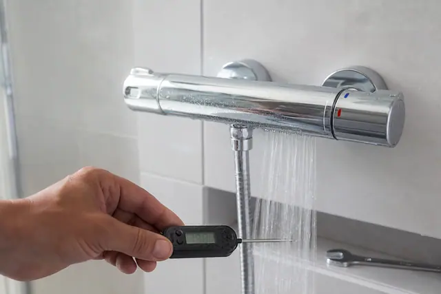 Mitigeur thermostatique de douche mural en cours de calibration avec un thermomètre