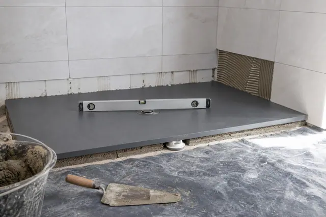 Receveur de douche extra-plat gris posé au sol d'une salle de bains en rénovation