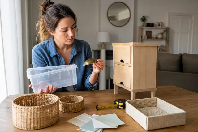 Bricoleuse comparant rangements, poignée de meuble et mètre ruban avant achat