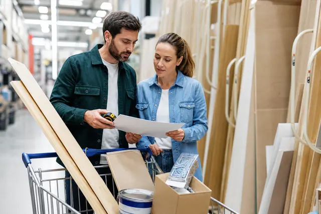 Couple comparant des matériaux et une liste dans un magasin de bricolage.