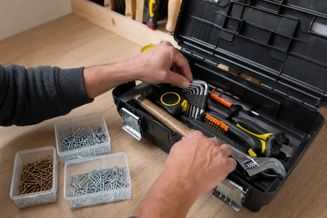 Caisse à outils débutant organisée avec mètre, niveau, tournevis, marteau et pinces.