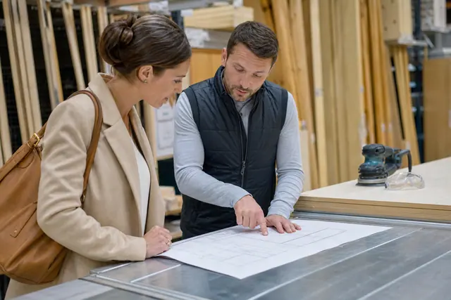 Cliente préparant une découpe de panneau avec un conseiller en magasin de bricolage.