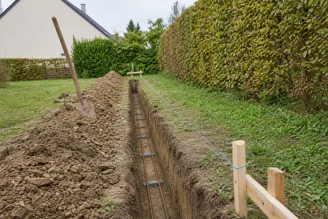 Fouille de fondation ouverte le long d’une limite de terrain avec aciers filants posés sur cales