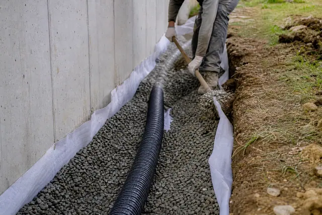Tranchée de drainage avec drain perforé et gravier au pied d'un mur de fondation