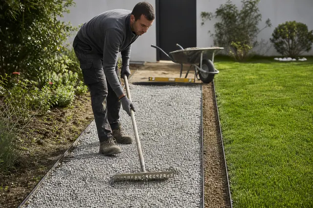 Allée de gravier bordée de métal en cours de nivellement dans un jardin