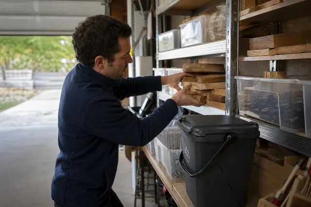 Coin réemploi organisé dans un garage avec chutes de bois et bacs transparents.