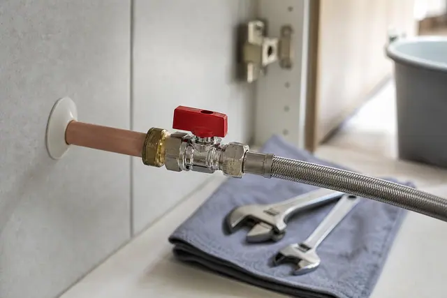 Robinet d'arrêt quart de tour neuf raccordé à un tube cuivre sous un évier de cuisine
