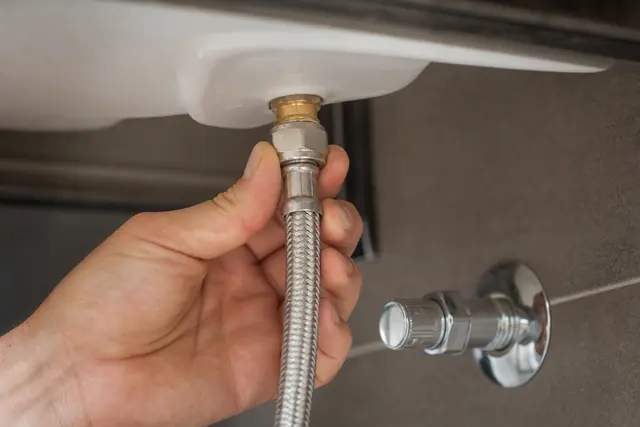 Flexible d'alimentation en inox tressé raccordé sous un évier de cuisine