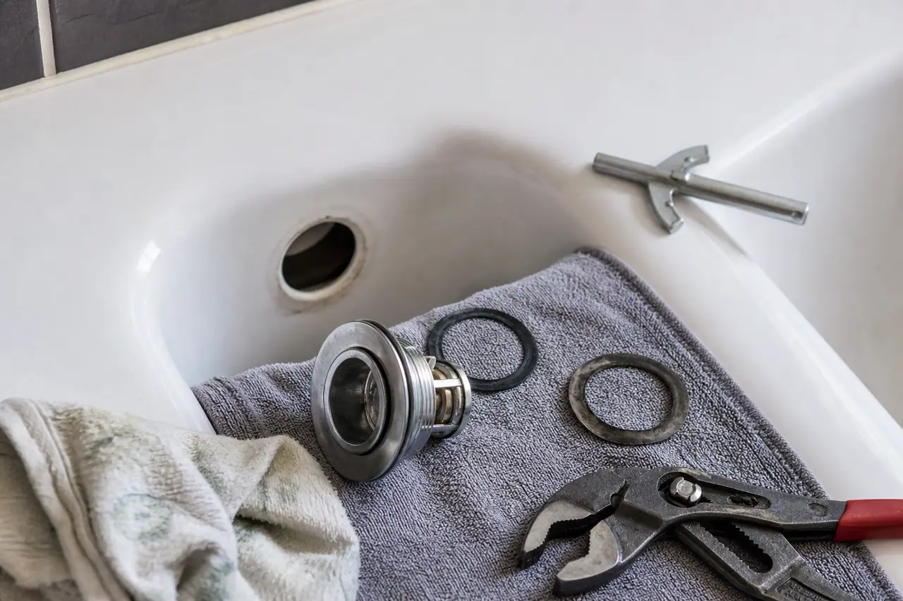 Bonde de baignoire démontée avec joint plat neuf posé à côté avant remontage