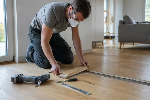 Personne réparant une lame endommagée sur un parquet massif en chêne