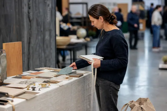Visiteuse compare des échantillons de bois et tissu dans un salon créatif.