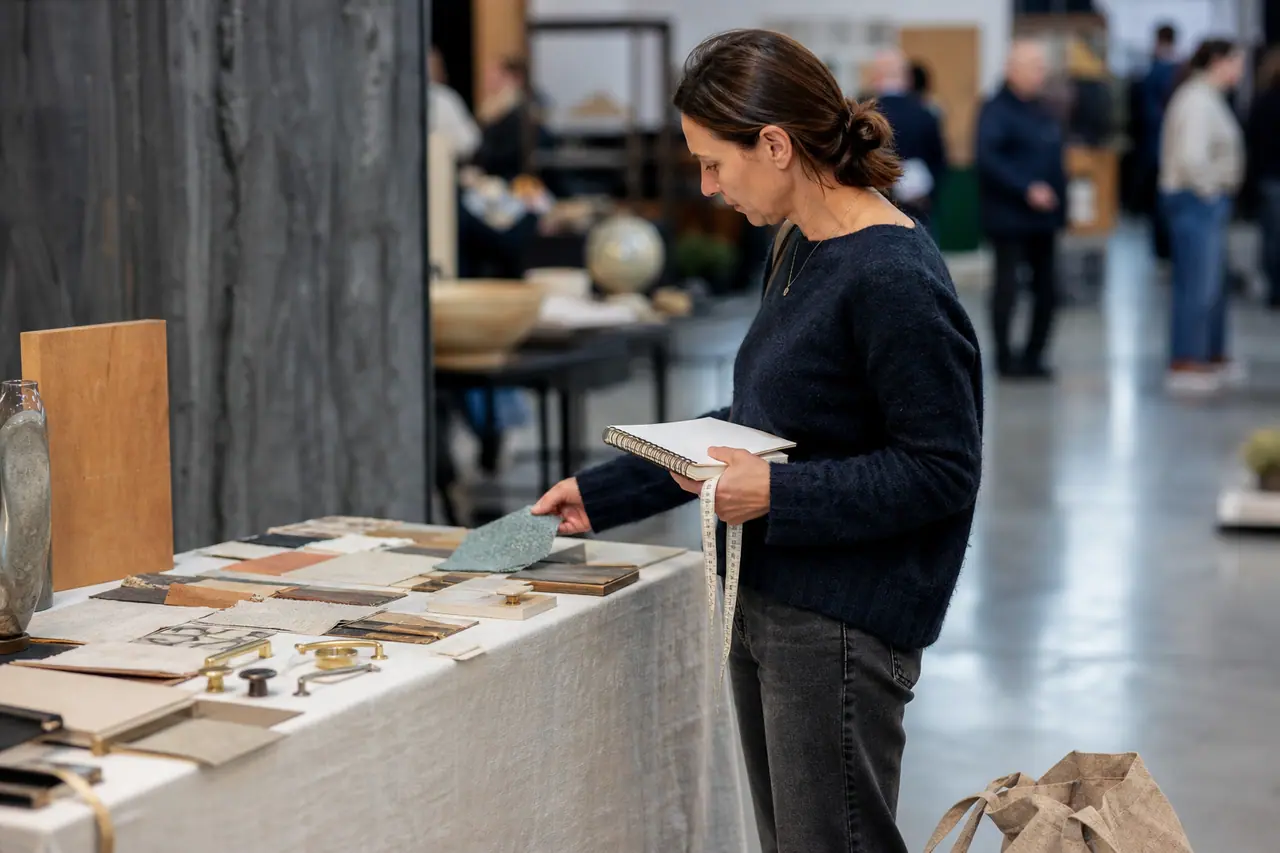 Visiteuse compare des échantillons de bois et tissu dans un salon créatif.