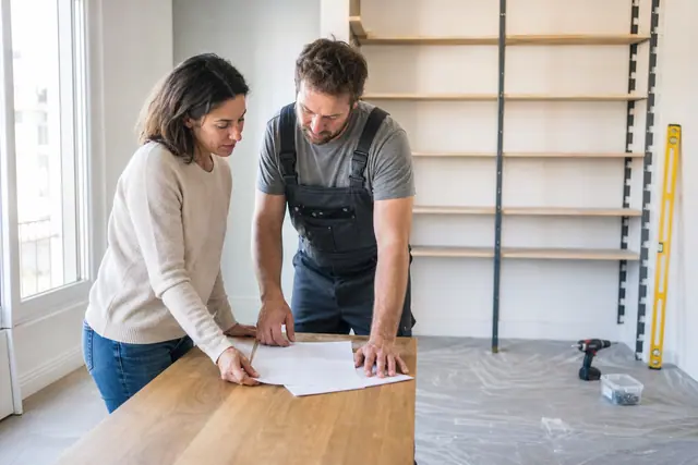 Propriétaire vérifiant un devis avec un professionnel avant une pose d’étagère.