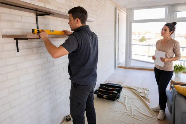 Professionnel vérifiant une étagère posée dans un appartement lumineux à La Rochelle.