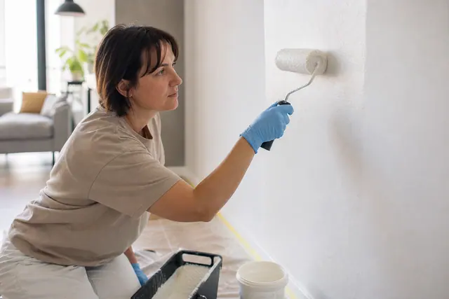 Application soignée d’une peinture murale à faibles émissions dans un séjour lumineux.