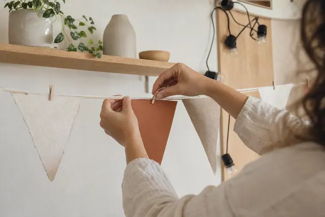 Guirlande de fanions en papier et tissu suspendue sur une tringle intérieure.