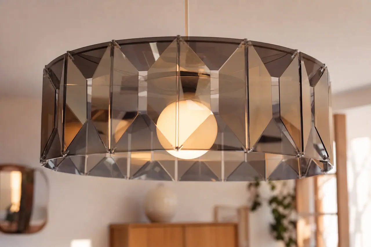 Suspension glossy ajourée en panneaux miroir au-dessus d’une table en bois.