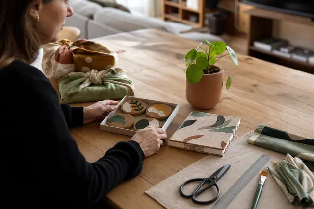 Cadeaux faits main en liège, tissu et pot décoré sur une table.