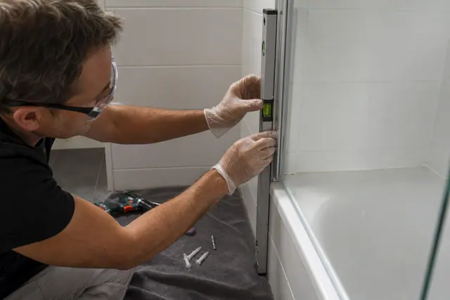 Réglage au niveau d’un pare-baignoire en verre sur baignoire carrelée