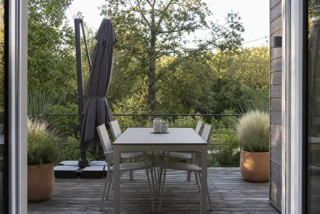 Terrasse aménagée avec table, parasol lesté, pots végétalisés et éclairage discret