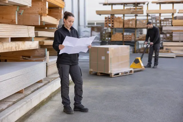Cliente préparant ses achats dans la cour d’un négoce de matériaux.