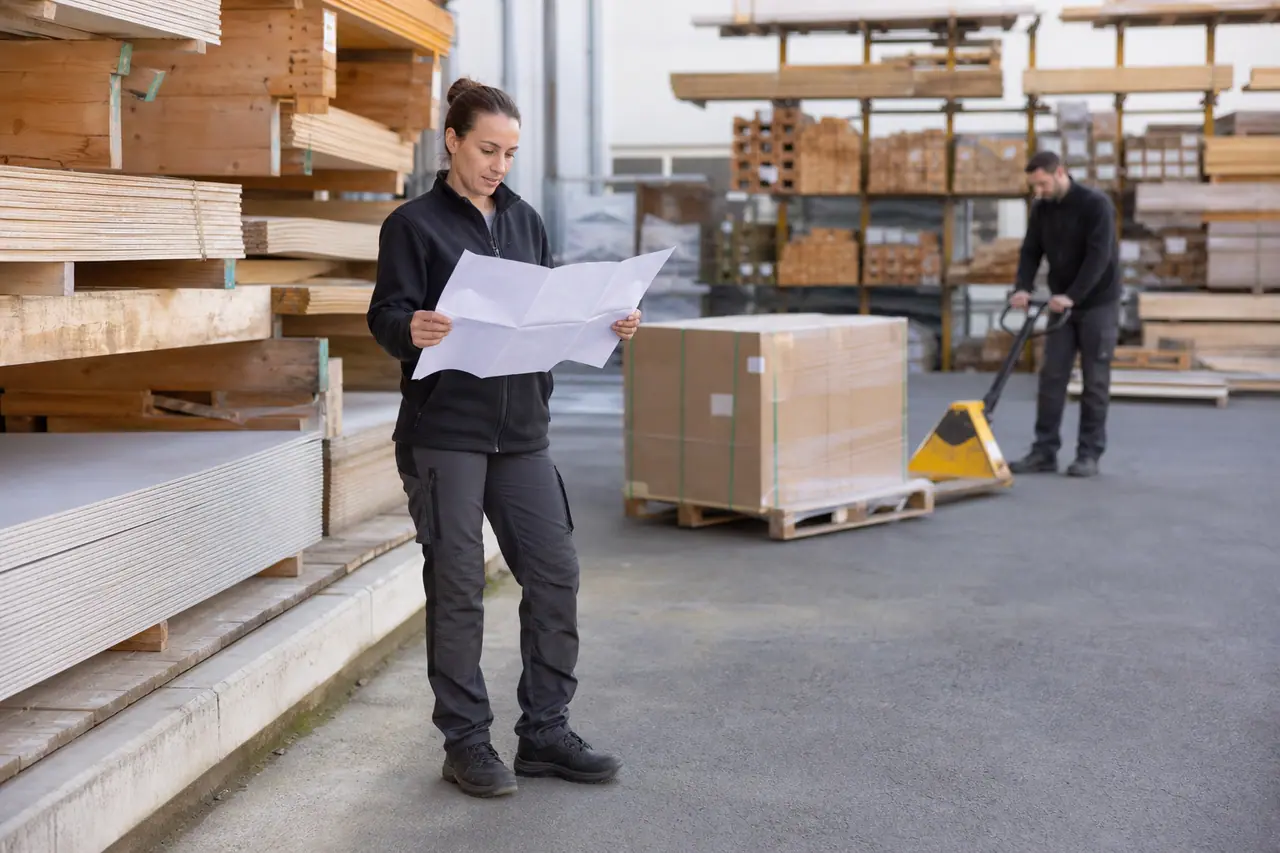 Cliente préparant ses achats dans la cour d’un négoce de matériaux.