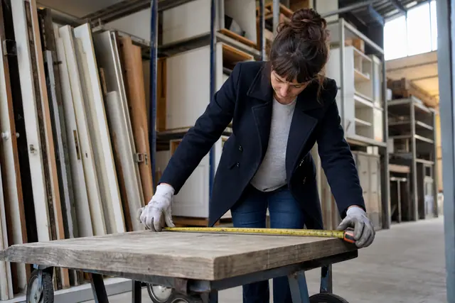Bricoleuse mesurant une planche de bois récupérée dans une matériauthèque