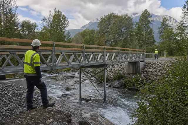 Ingénieur inspectant une passerelle modulaire temporaire au-dessus d’un torrent alpin.