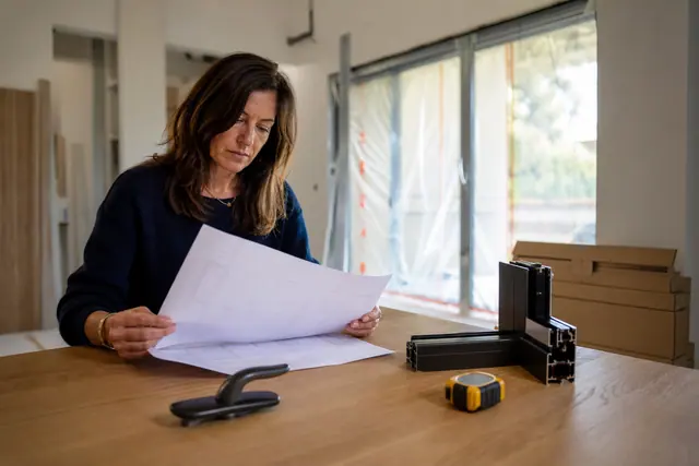 Propriétaire vérifiant une commande de fenêtres dans une maison en rénovation.