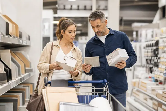Couple comparant robinetterie et carrelage dans un magasin de bricolage.
