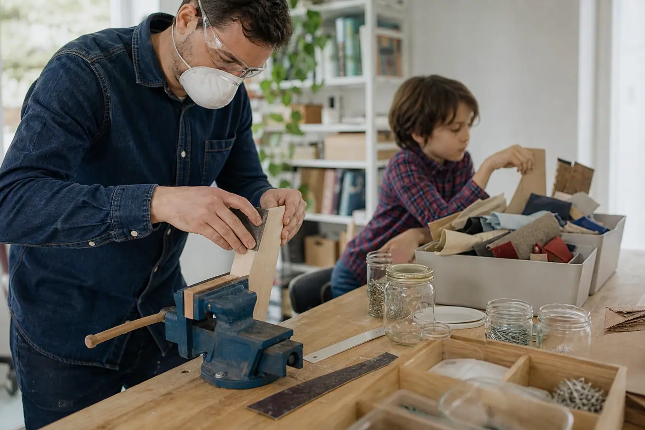 Un adulte ponce une planche pendant qu’un enfant trie cartons et textiles.