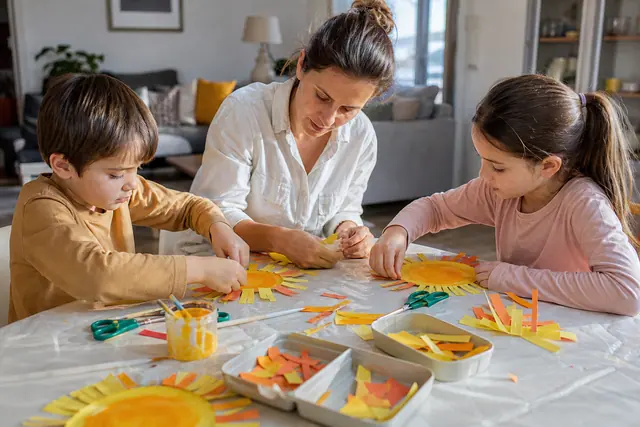 Enfants créant une guirlande estivale en carton sur une table protégée