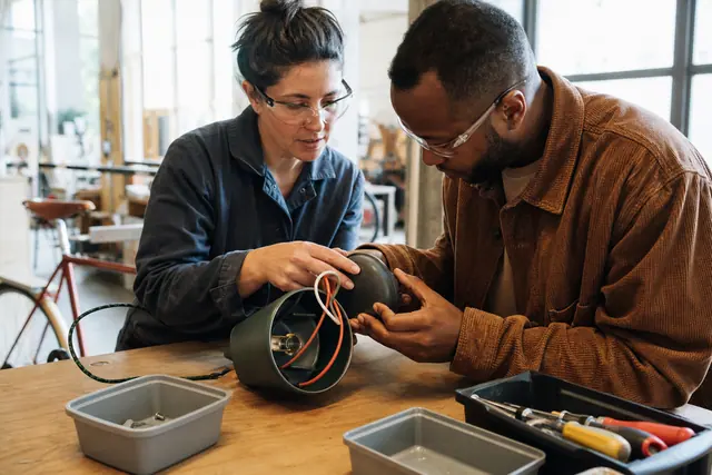 Participants examinent une lampe débranchée sur un établi d’atelier participatif à Strasbourg.
